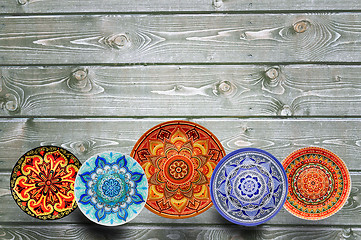 Image showing Set of decorative ceramic plates hand painted dot pattern with acrylic paints on a gray wooden background. Copy space.