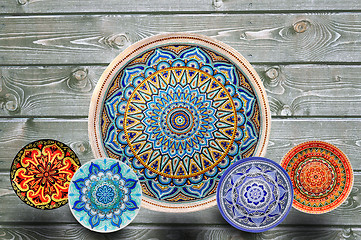 Image showing Set of decorative ceramic plates hand painted dot pattern with acrylic paints on a gray wooden background. Copy space.