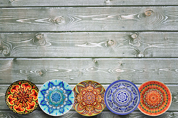 Image showing Set of decorative ceramic plates hand painted dot pattern with acrylic paints on a gray wooden background. Copy space.