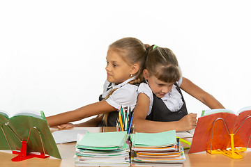 Image showing Two girls share a desk and push each other\'s backs