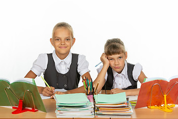 Image showing Two schoolgirls at a desk, one funny, the other upset