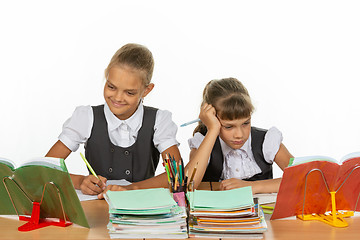 Image showing Two schoolgirls at a desk, one excellent student, the second two-year student