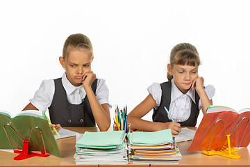 Image showing Sad schoolgirls look at a book in a lesson