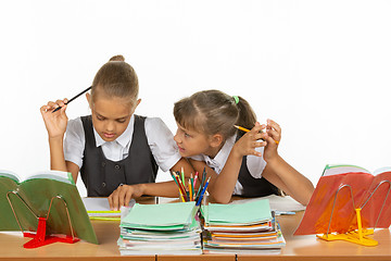 Image showing One girl pestering another at a lesson at school