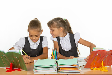 Image showing Girl looks at what her desk neighbor writes in a notebook