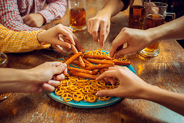 Image showing people, leisure, friendship and communication concept - happy friends drinking beer, talking and clinking glasses at bar or pub