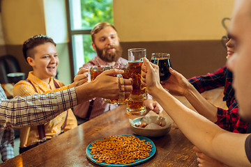 Image showing people, leisure, friendship and communication concept - happy friends drinking beer, talking and clinking glasses at bar or pub