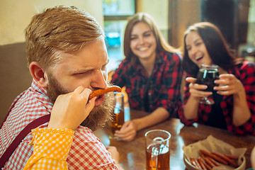 Image showing people, leisure, friendship and communication concept - happy friends drinking beer, talking and clinking glasses at bar or pub