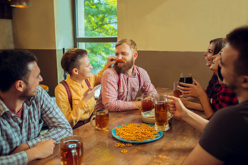 Image showing people, leisure, friendship and communication concept - happy friends drinking beer, talking and clinking glasses at bar or pub