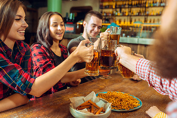 Image showing people, leisure, friendship and communication concept - happy friends drinking beer, talking and clinking glasses at bar or pub