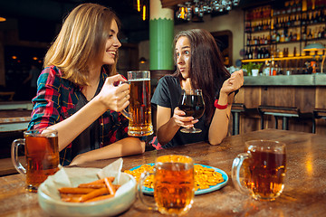 Image showing people, leisure, friendship and communication concept - happy friends drinking beer, talking and clinking glasses at bar or pub