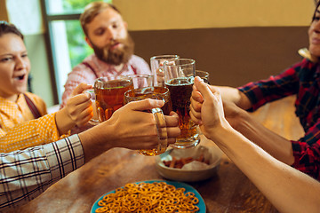 Image showing people, leisure, friendship and communication concept - happy friends drinking beer, talking and clinking glasses at bar or pub