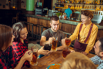 Image showing people, leisure, friendship and communication concept - happy friends drinking beer, talking and clinking glasses at bar or pub