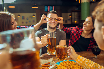 Image showing people, leisure, friendship and communication concept - happy friends drinking beer, talking and clinking glasses at bar or pub