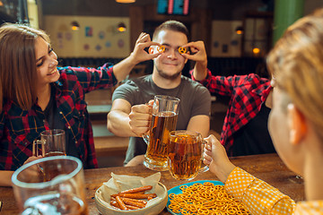 Image showing people, leisure, friendship and communication concept - happy friends drinking beer, talking and clinking glasses at bar or pub