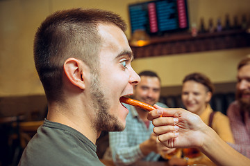 Image showing people, leisure, friendship and communication concept - happy friends drinking beer, talking and clinking glasses at bar or pub