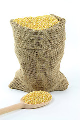 Image showing Millet grains in burlap bag and over wooden spoon. 