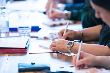 Image showing close up of business people taking notes