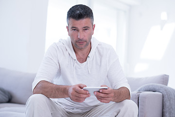 Image showing young man using a mobile phone  at home