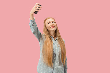 Image showing Portrait of a happy smiling casual girl showing blank screen mobile phone isolated over pink background