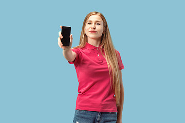 Image showing Portrait of a confident casual girl showing blank screen mobile phone isolated over blue background