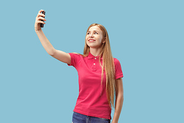 Image showing Portrait of a happy smiling casual girl showing blank screen mobile phone isolated over blue background