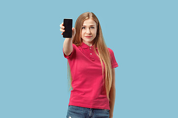 Image showing Portrait of a confident casual girl showing blank screen mobile phone isolated over blue background