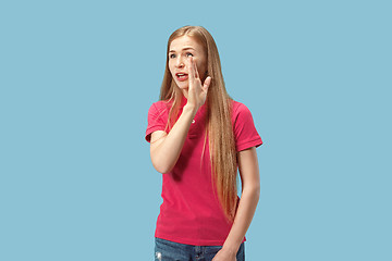 Image showing The young woman whispering a secret behind her hand over blue background