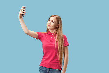 Image showing Portrait of a happy smiling casual girl showing blank screen mobile phone isolated over blue background