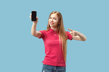 Image showing Portrait of a confident casual girl showing blank screen mobile phone isolated over blue background