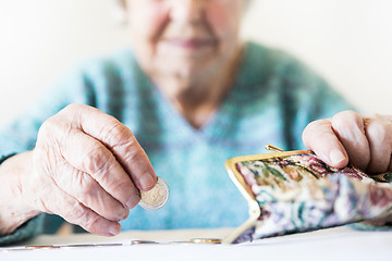 Image showing Detailed closeup photo of unrecognizable elderly womans hands counting remaining coins from pension in her wallet after paying bills.