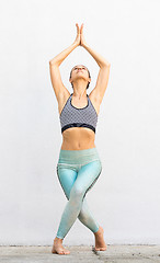 Image showing Fit sporty active girl in fashion sportswear doing yoga fitness exercise in front of gray wall, outdoor sports, urban style