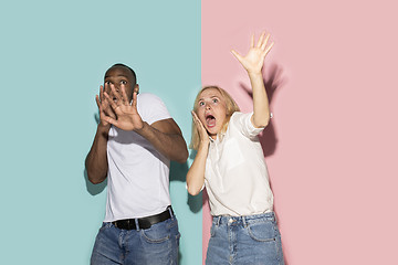 Image showing Portrait of the scared couple on pink and blue studio background