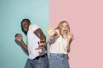 Image showing Portrait of the scared couple on pink and blue studio background