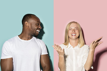 Image showing happy afro man and woman. Dynamic image of caucasian female and afro male model on pink studio.