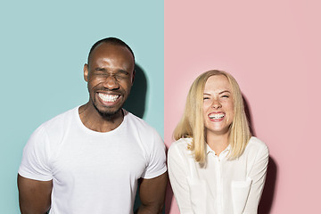 Image showing happy afro man and woman. Dynamic image of caucasian female and afro male model on pink studio.