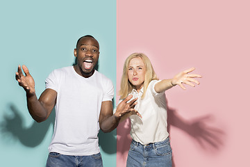 Image showing The afro surprised couple watching sports match on tv at home, successful game. Different emotions concept. Studio shot with african american man and woman