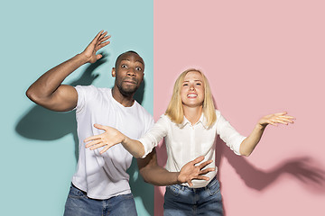 Image showing The afro surprised couple watching sports match on tv at home, successful game. Different emotions concept. Studio shot with african american man and woman