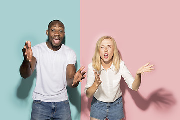 Image showing The afro surprised couple watching sports match on tv at home, successful game. Different emotions concept. Studio shot with african american man and woman