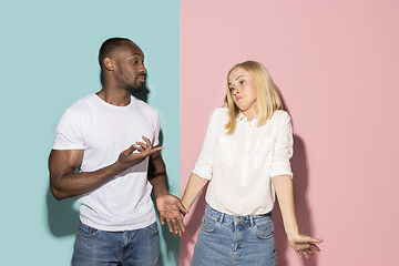 Image showing Beautiful female and male portrait on pink and blue studio backgroud. The young emotional couple