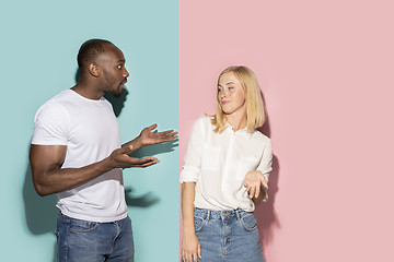 Image showing Beautiful female and male portrait on pink and blue studio backgroud. The young emotional couple