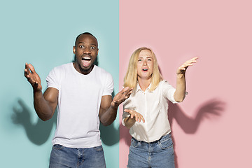 Image showing The afro surprised couple watching sports match on tv at home, successful game. Different emotions concept. Studio shot with african american man and woman