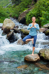 Image showing Woman in yoga asana Vrikshasana tree pose at waterfall outdoors