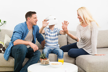 Image showing Happy family at home on living room sofa having fun playing games using virtual reality headset