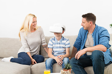 Image showing Happy family at home on living room sofa having fun playing games using virtual reality headset