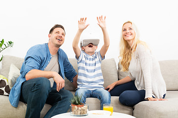 Image showing Happy family at home on living room sofa having fun playing games using virtual reality headset