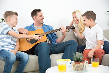 Image showing Happy caucasian family smiling, playing guitar and singing songs together at cosy modern home