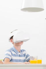Image showing Amazed child using virtual reality headsets while sitting at the dinner table.