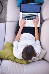 Image showing Young woman using laptop at home top view