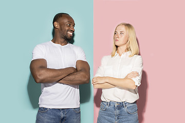 Image showing Closeup portrait of young couple, man, woman. One being excited happy smiling, other serious, concerned, unhappy on pink and blue background. Emotion contrasts